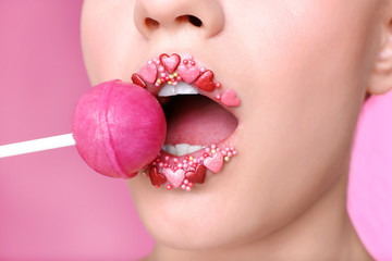Beautiful young woman with creative makeup and lollipop on color background, closeup