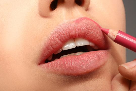 Fototapeta Lips of beautiful young woman applying makeup, closeup