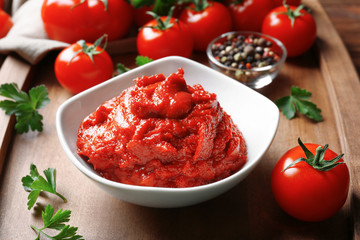Delicious tomato paste in bowl with ingredients on tray, closeup