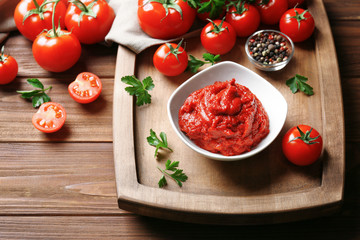 Delicious tomato paste in bowl with ingredients on wooden background