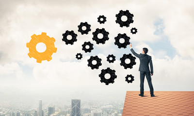 Businessman standing with back on house brick roof and drawing. 