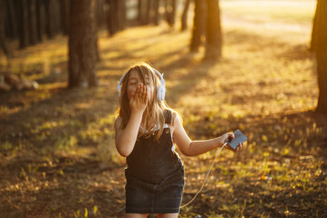 girl Listening to music with headphones in the woods