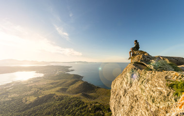 A traveler on the top of the mountain is enjoying the stunning view at sunset in Sardinia, Italy.