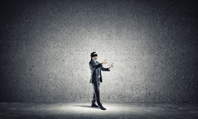 Business concept of risk with businessman wearing blindfold in empty concrete room