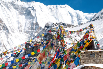 Buddyjskie flagi modlitewne w Annapurna Base Camp z ośnieżonymi górami w tle.. 