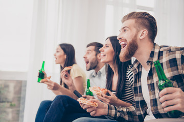 Goal! Very excited youth is having fun by watching football match and drink beer, eat pizza at home indoors