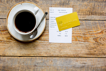 restaurant bill, card and coffee on wooden table background top view space for text