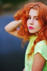 Fototapeta premium Beautiful summer portrait of pensive red-haired girl on the background of river.