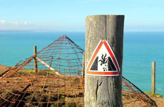 Warning sign indicating danger of falling, near the covered opening of a disused tin mine shaft