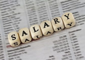 Salary word built with letter cubes on newspaper background