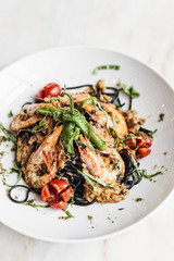 gourmet grilled prawn and vegetables on black squid ink pasta