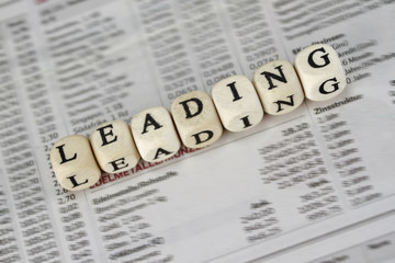 Leading word built with letter cubes on newspaper background