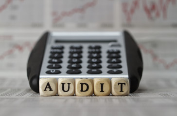 Audit word built with letter cubes on newspaper background
