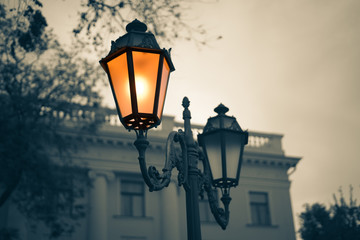 Fototapeta na wymiar Black and white picture of Old Vintage street light with old building on background. Lamp light is colored.
