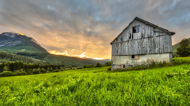Sunset over mountains and old barn in norway