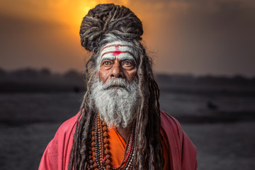 Portrait of sadhu standing with sunrise behind him, Varanasi, India.