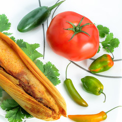 Mexican tamales made of corn and chicken with chiles and tomato isolated on white