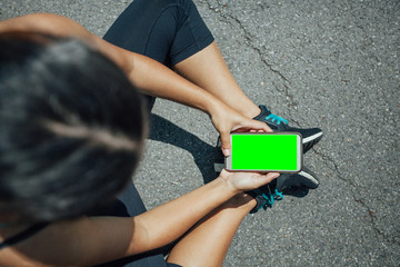 Tired fitness woman after workout and use smartphone with green screen