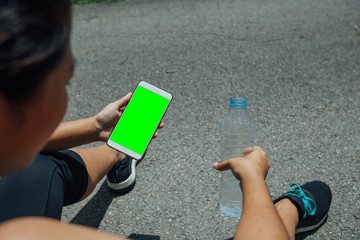 Tired fitness woman after workout and use smartphone with green screen