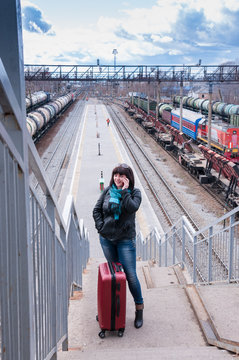 Girl with a suitcase talking on phone at  train station