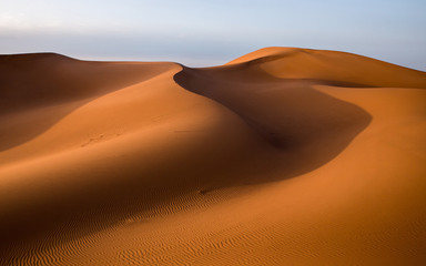Fototapeta na wymiar Waves of sand dunes in the Sahara desert at sunset