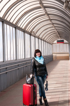 Girl with a suitcase is walking along train station