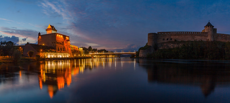 Opposition of two medieval fortresses on the river Narva at blue hour, Estonia and Russia border. Wide panoramic view