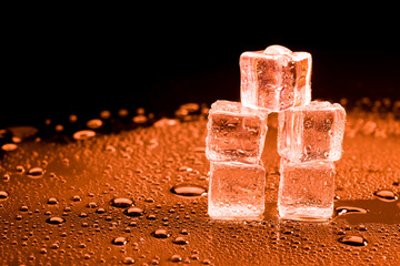 Water drop with ice cubes on lighting red background.