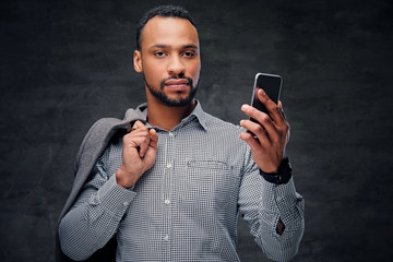 Casually dressed black American male holds smart phone.