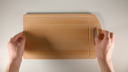 TOP VIEW: Human hands puts a wooden cutting board on a white table
