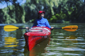 A girl rafts down the river on a kayak.