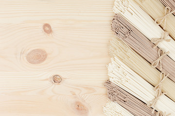 Raw asian noodles on soft beige wooden board with copy space as decorative border frame, top view.