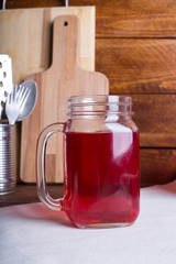 Fresh and healthy red Fruit juice drink  in a glass and jug on the wooden brown table background. Side view.