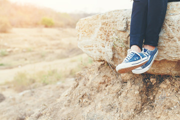 Girl legs with shoes and sitting on giant stone.
