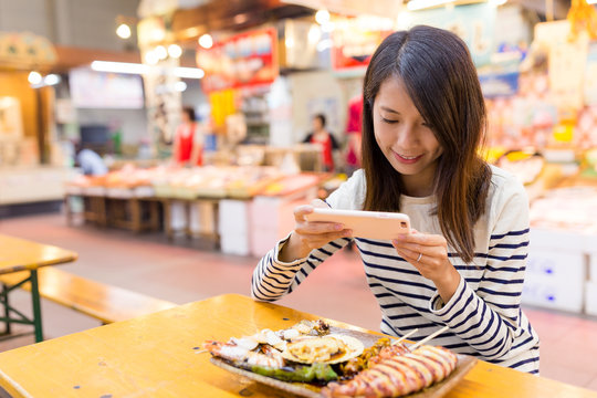 Woman taking photo on her dish in wet market of Japan