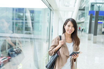 Woman holding cellphone and passport in airport