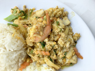 fried seafood with curry powder with rice on white plate with white background.