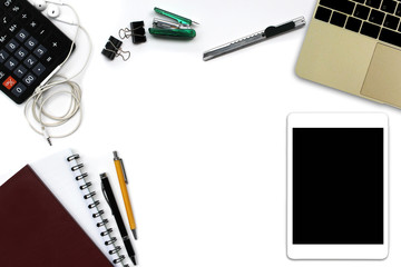 White office desk with tablet computer with black screen, pen, notepad, laptop computer and supplies. Top view with copy space