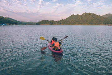 holidays, vacation, love and friendship concept - couple is kayaking in the beautiful lake at Mae Ngat dam