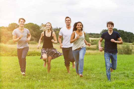 gruppe junger leute rennt über eine wiese im sommer