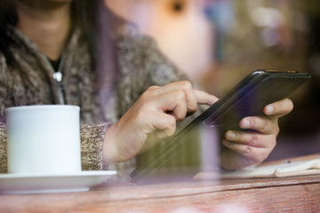 Woman hand using digital tablet in the cafe in rainy day in vintage color tone