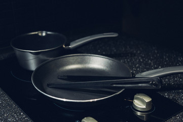 Metal black frying pan with a non-stick coating on electric stove. Teflon frying pan..Close up an electrical kitchen induction ceramic hob..Modern kitchen. Steel pot and pan on the induction cooker