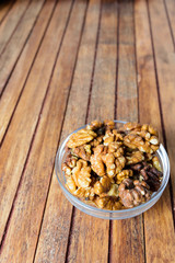 Walnuts in bowl over wooden background