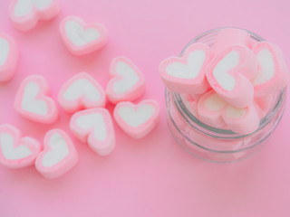 Closeup of sweet marshmallow in the shape of heart in jar on pink background. Concept about love and relationship. (Soft Style for Background)