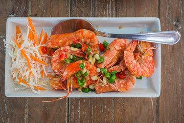 Fried shrimps fish sauce on a plate with vegetables on wooden table