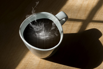 Lighting from window with hot white coffee cup on the wooden.