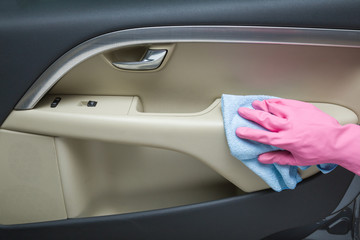 Hand in rubber protective glove with rag cleaning a car interior's door. Early spring cleaning or regular clean up.