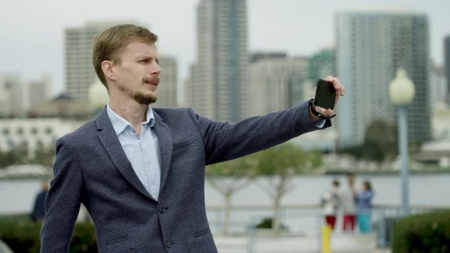 Serious young man is taking a selfshot on a street in Coronado