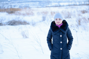 Portrait of a young girl in a blue coat with a fur collar and a gray hat.