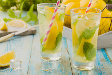 lemonade with mint on rocks served in a glass with a straw